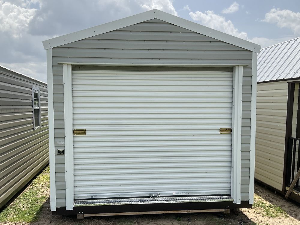 Front view of a white metal storage shed with closed roll-up door