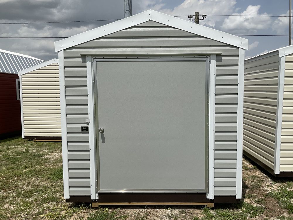 Small white outdoor storage shed with a closed door and gabled roof