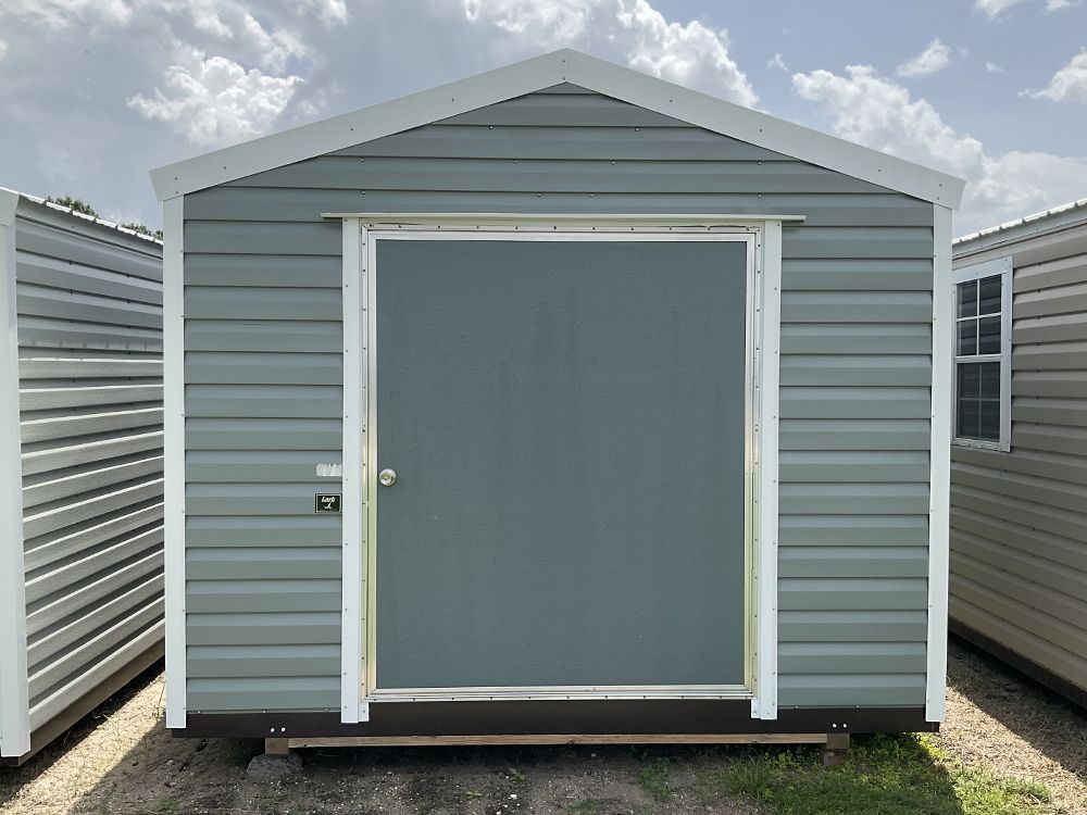 Gray storage shed with a centered white-framed door and small windows on both sides