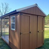 Wooden shed with brown doors and a screened side porch in a grassy yard