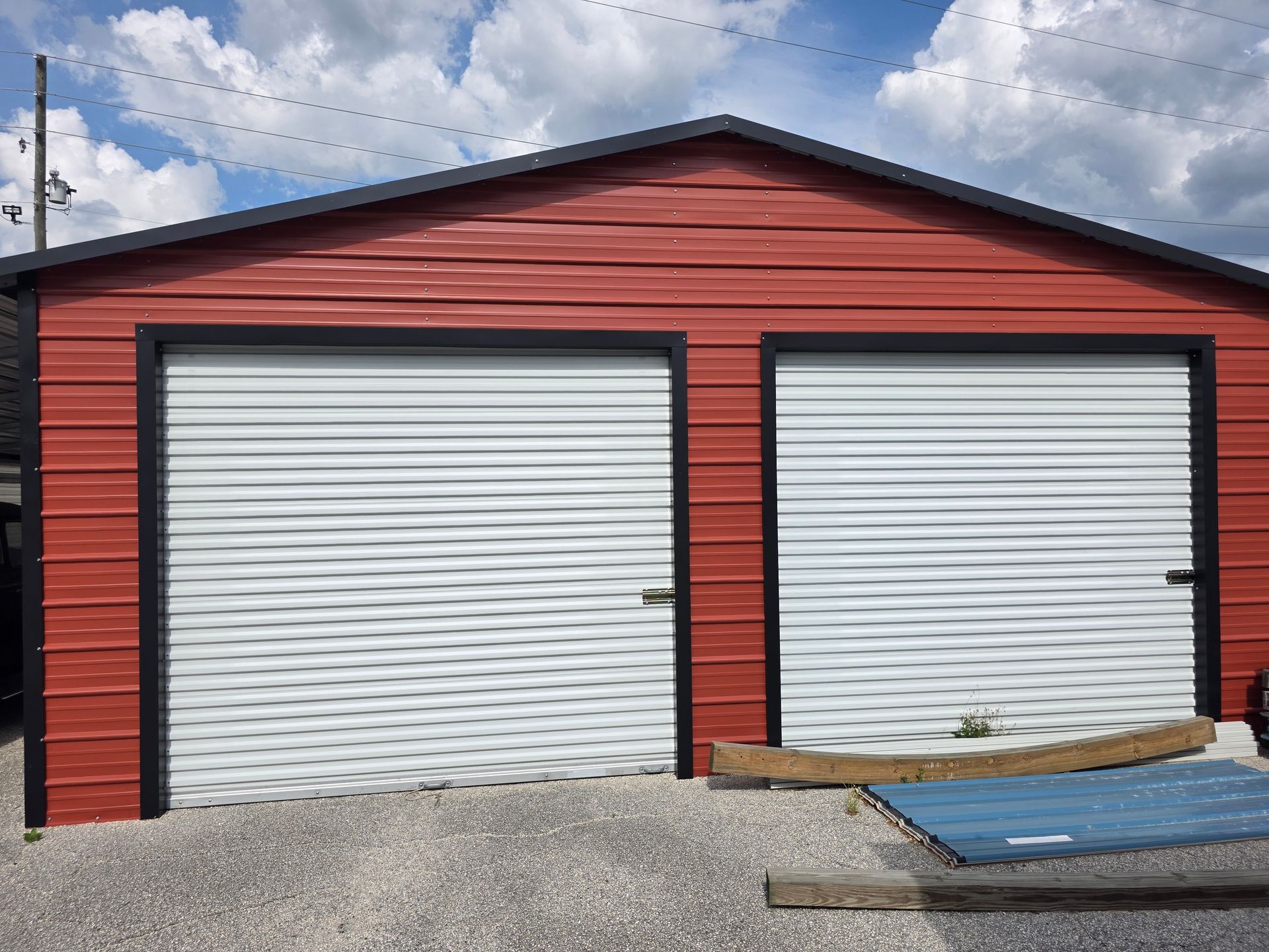 Red two-bay garage with white roll-up doors under a cloudy sky