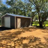 Small brown shed with white trim in a sunny wooded yard