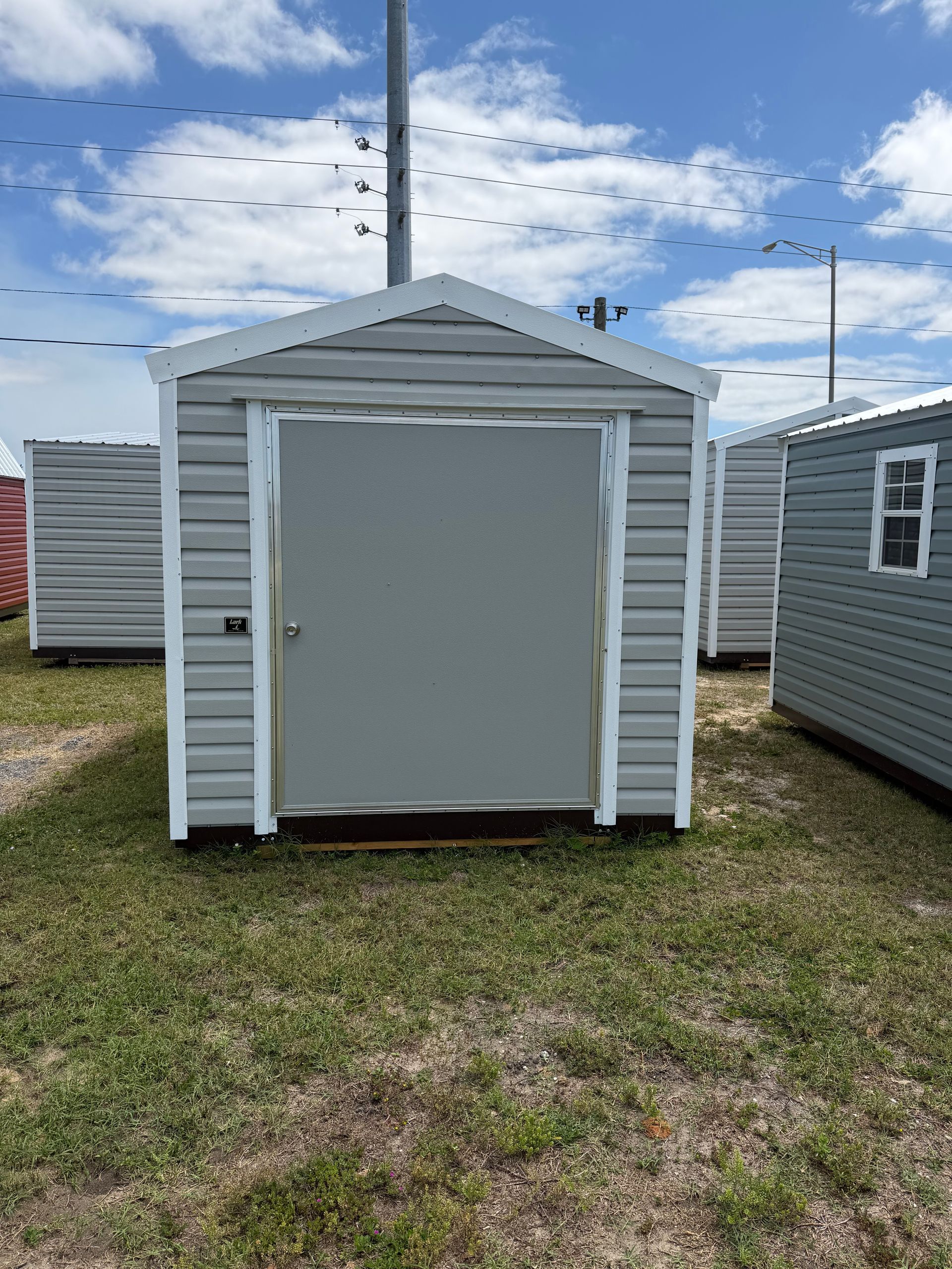 Small mint-green cabin with a metal roof raised on blocks in a sunny grassy yard.
