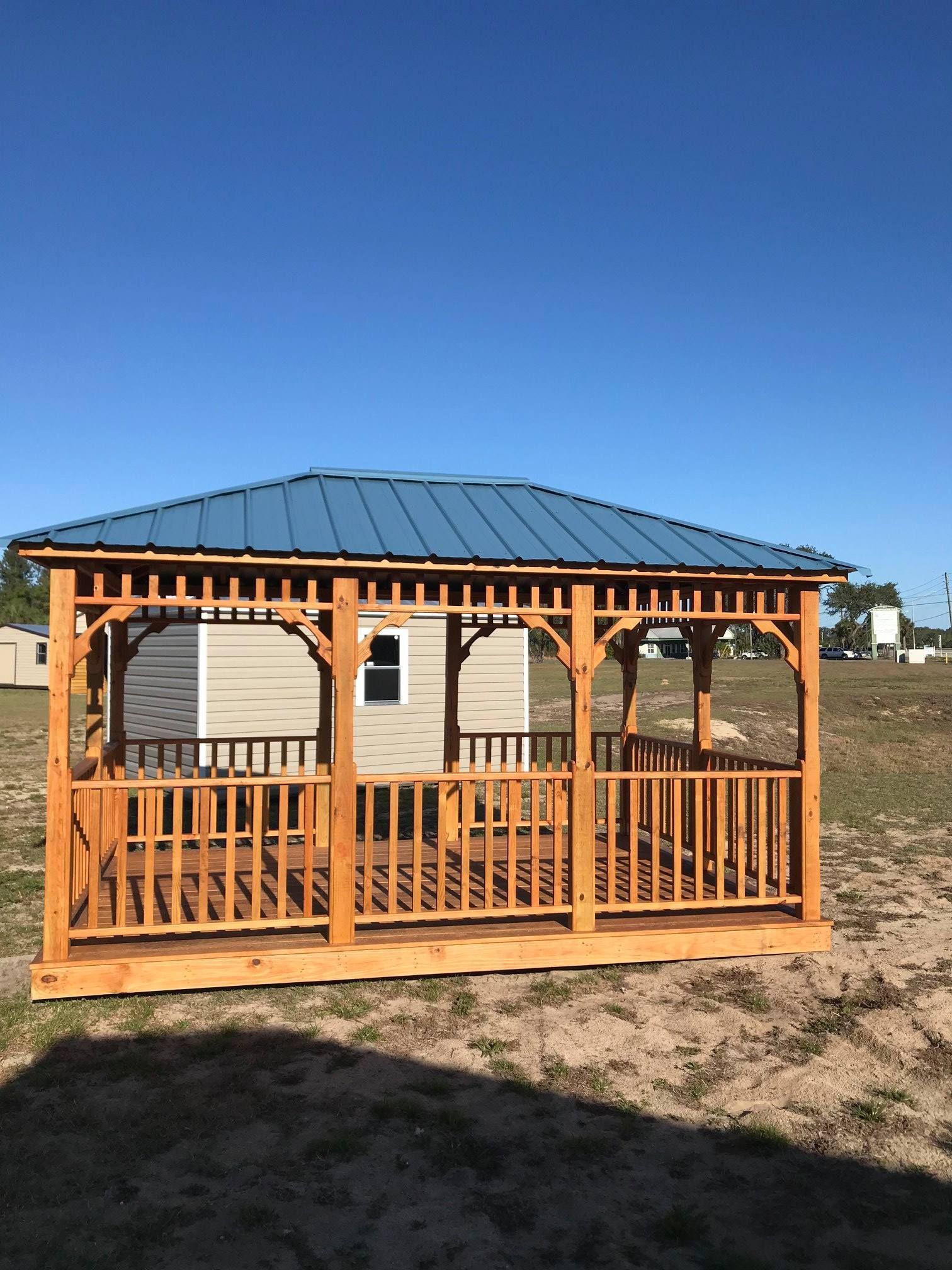 Wooden gazebo with blue metal roof in a sunny open field