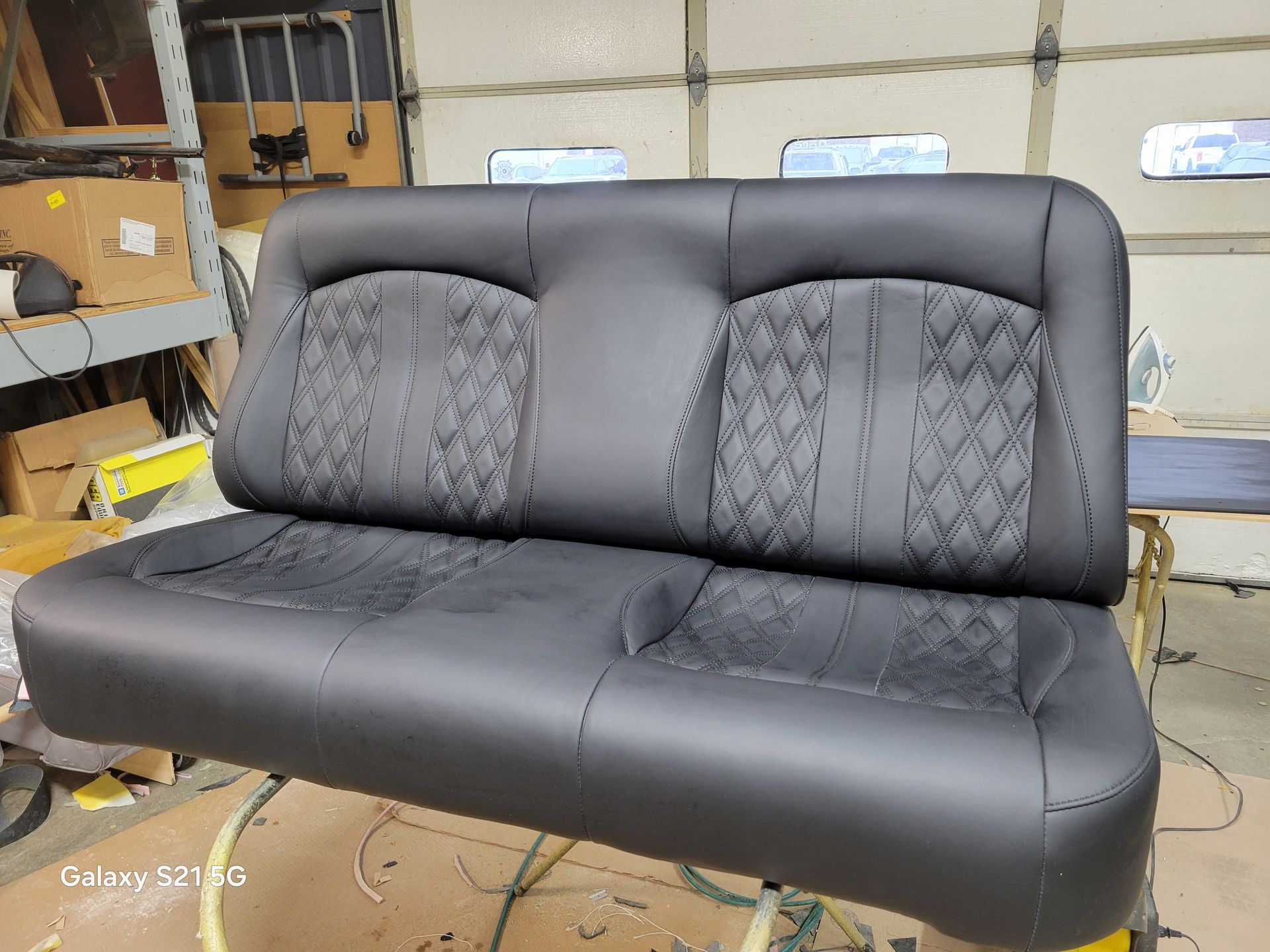 Black two-seat sofa with patterned gray back cushions in a workshop setting
