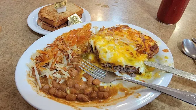 A plate of food with beans , eggs , cheese and hash browns on a table.