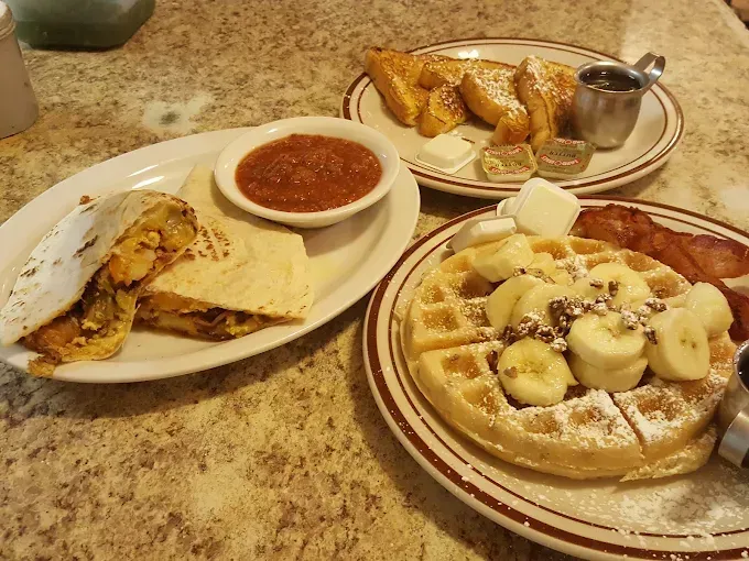 A table topped with plates of food including waffles french toast and quesadillas