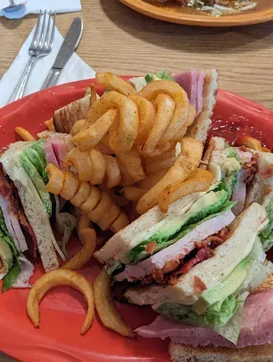 A red plate topped with a club sandwich and french fries.