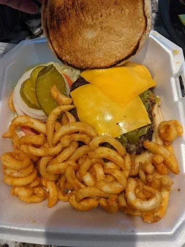 A hamburger and french fries are in a styrofoam container.