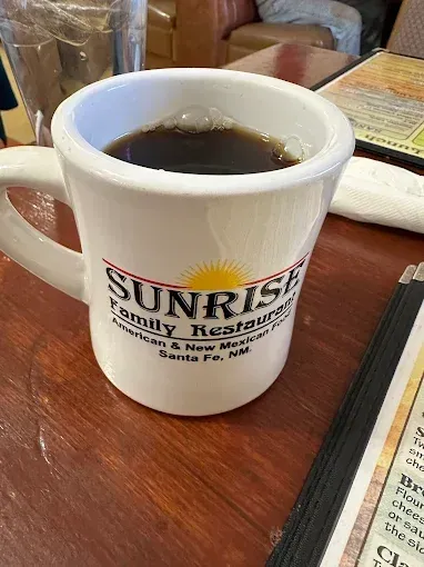 A cup of coffee is sitting on a table next to a menu.