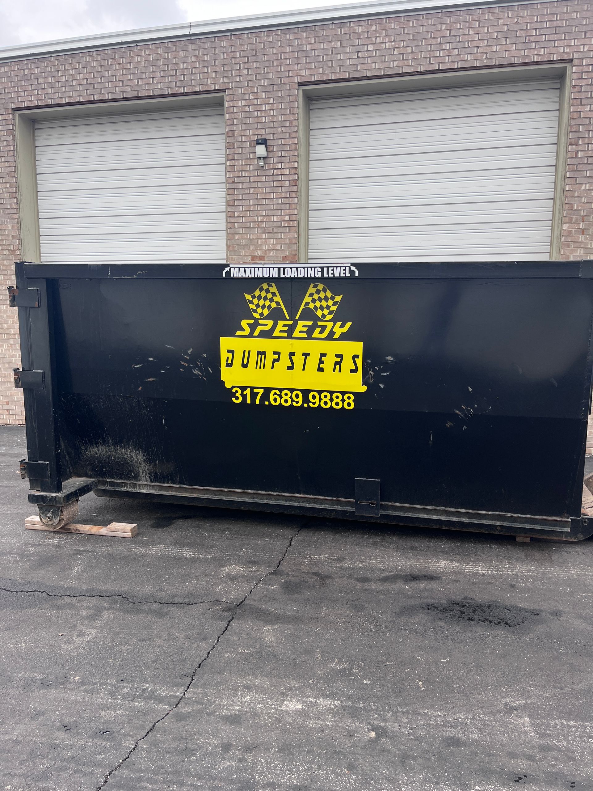 Black dumpster with yellow logo 