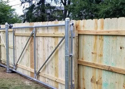 Wooden fence with metal gate and frame; green grass background.