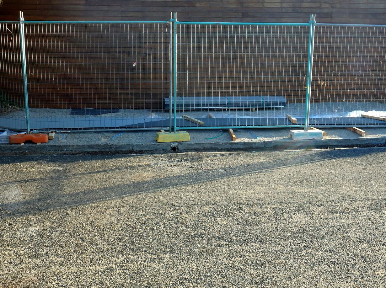 Wooden backyard fence with a small gate beside a driveway and parked car