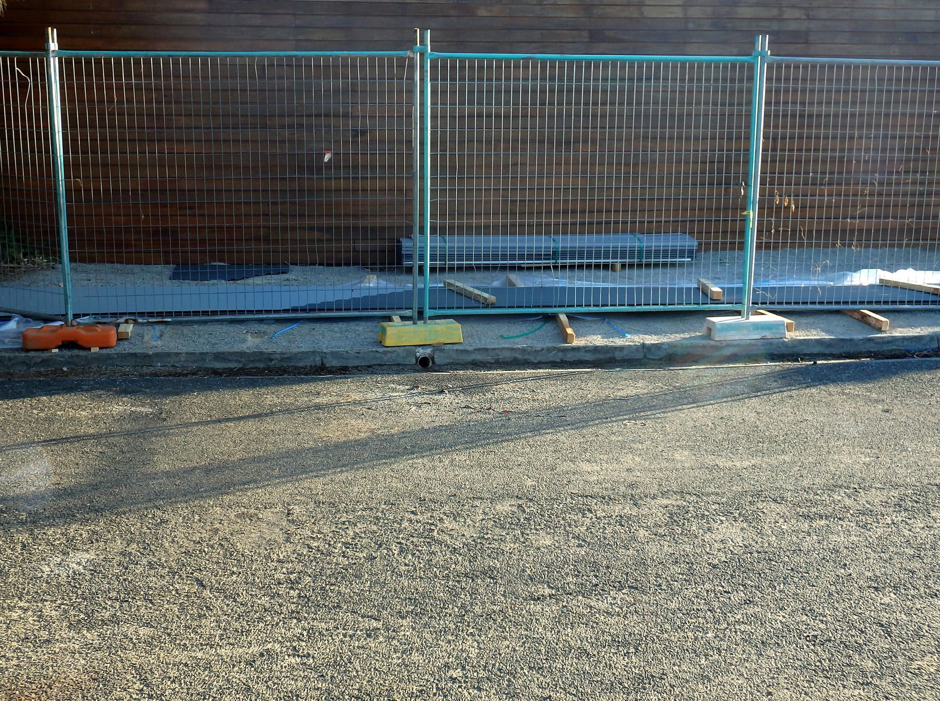 Wooden backyard fence with a small gate beside a driveway and parked car