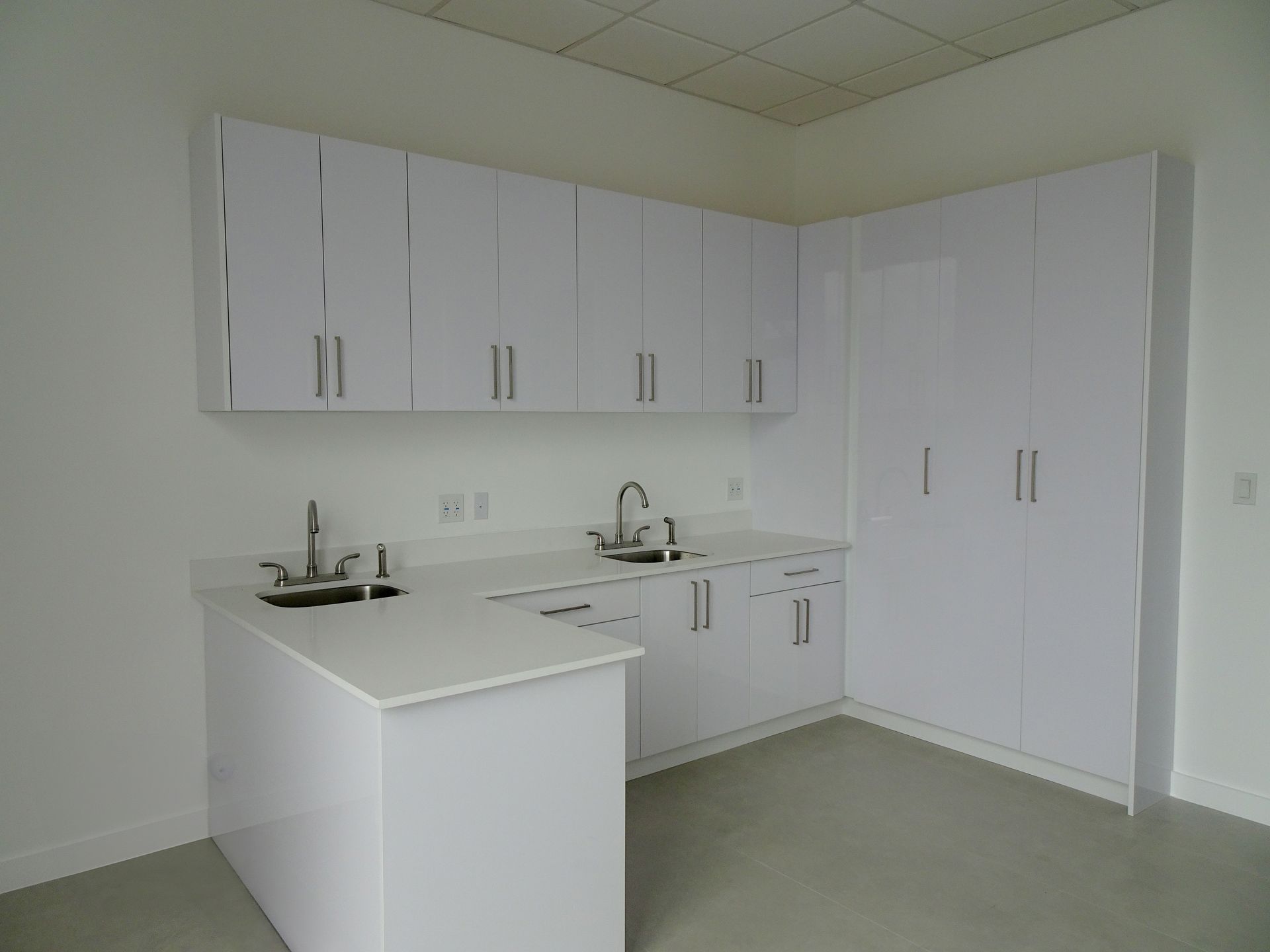 An empty kitchen with white cabinets and a sink