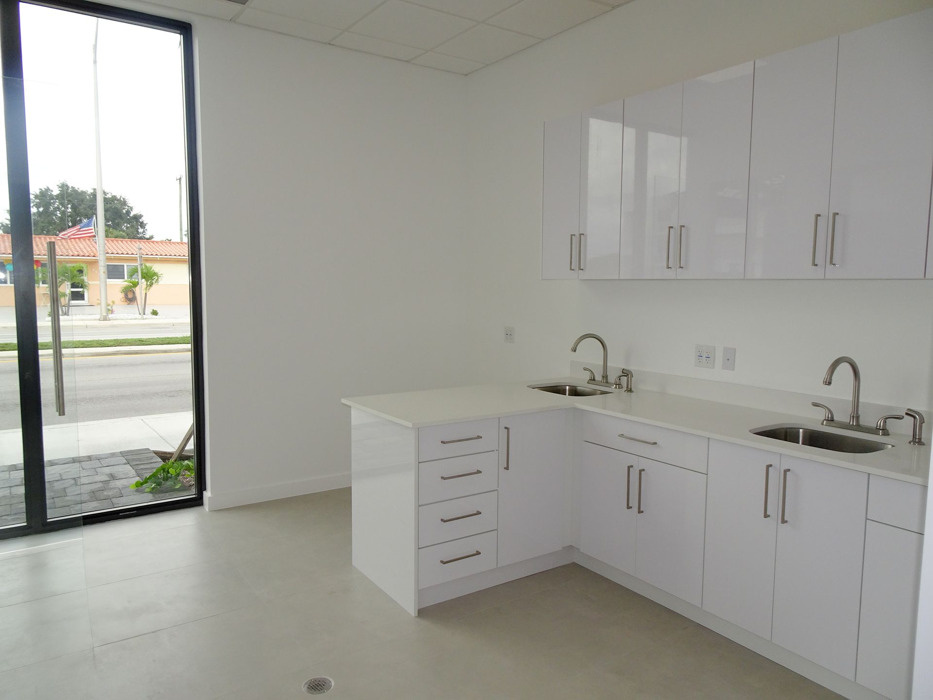 An empty kitchen with white cabinets and a sink