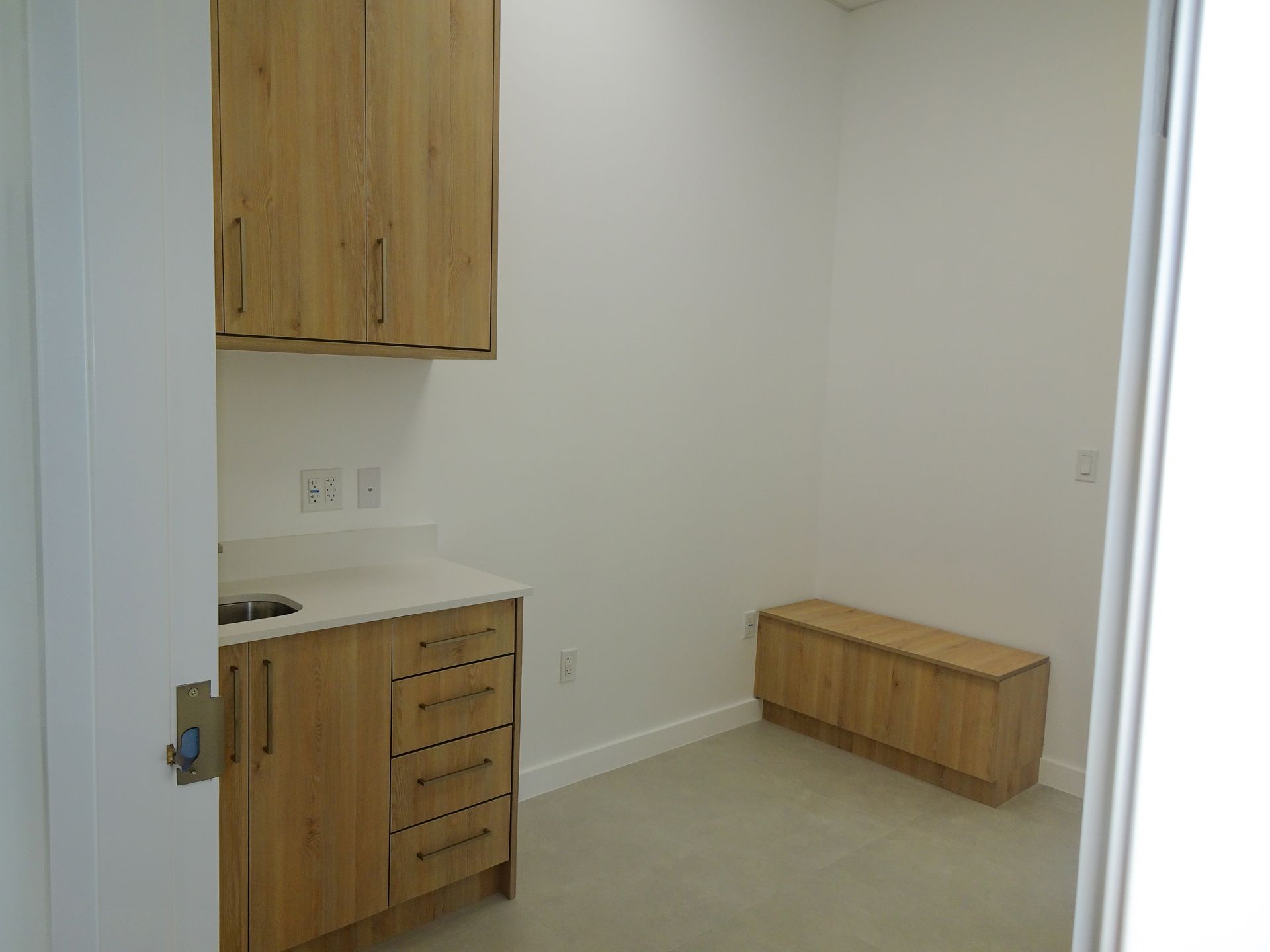 A kitchen with wooden cabinets , a sink , and a bench.
