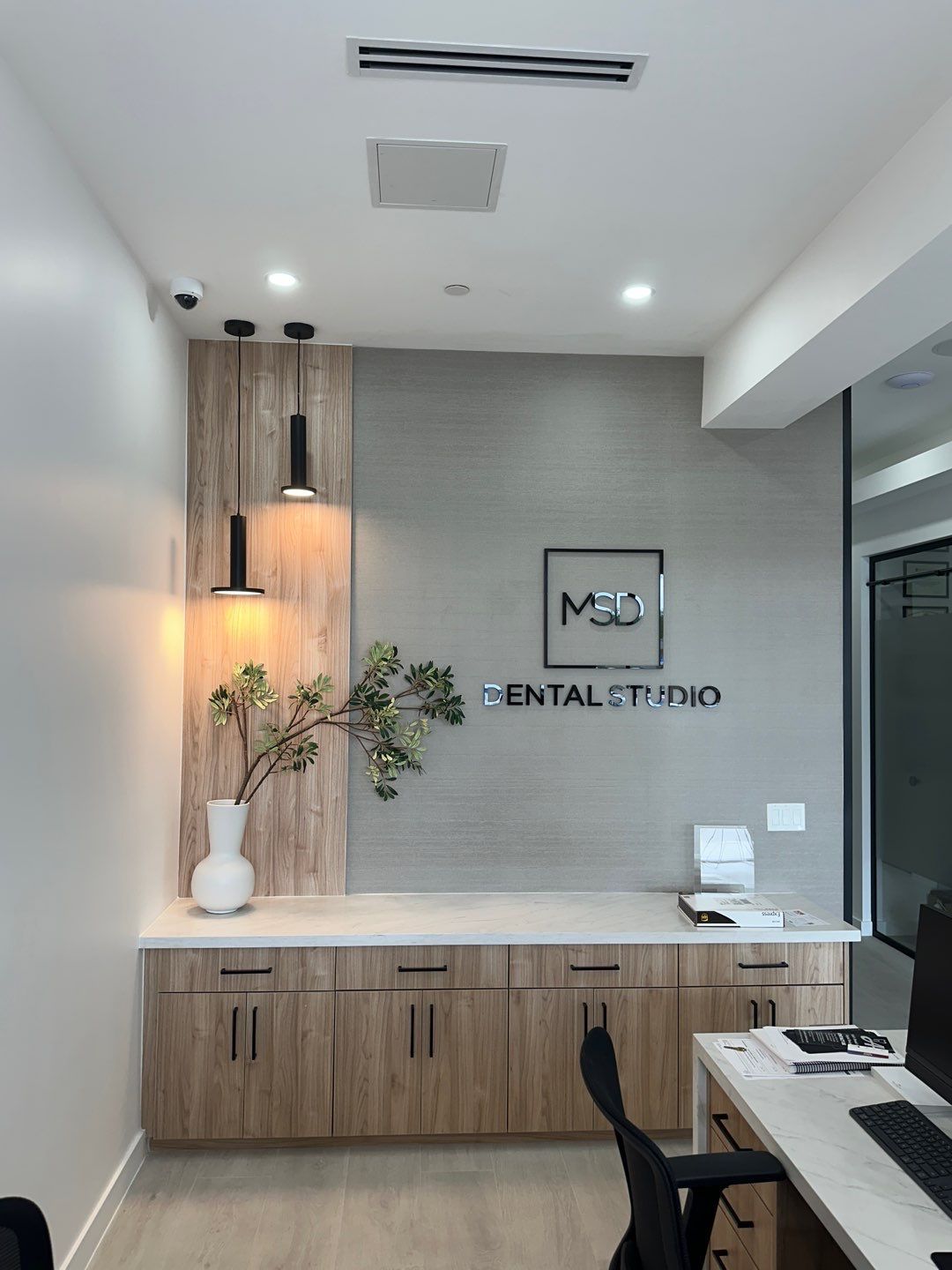 A dental office with a desk and chairs and a sign on the wall.