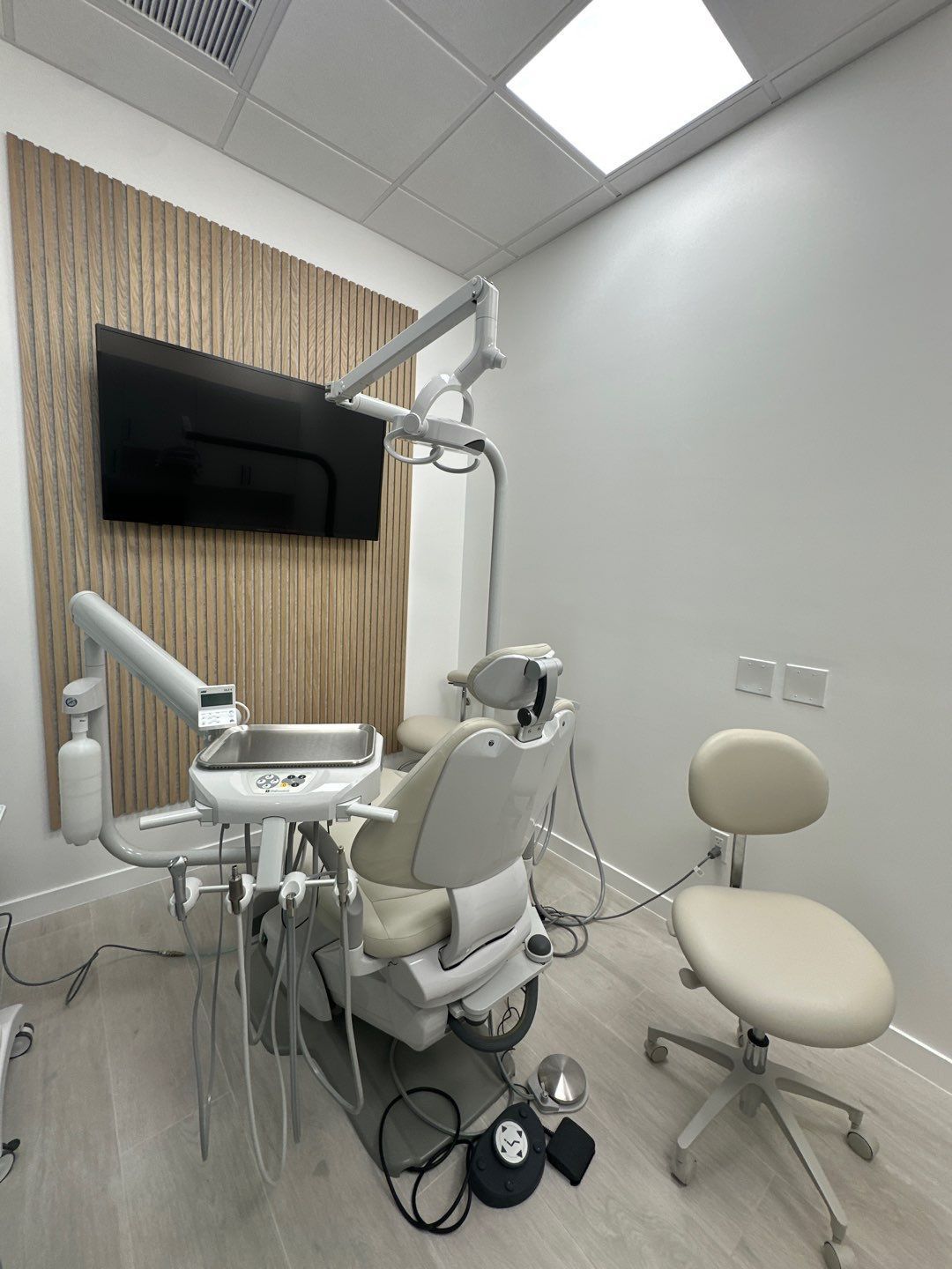 A dental office with a dental chair and a television on the wall.