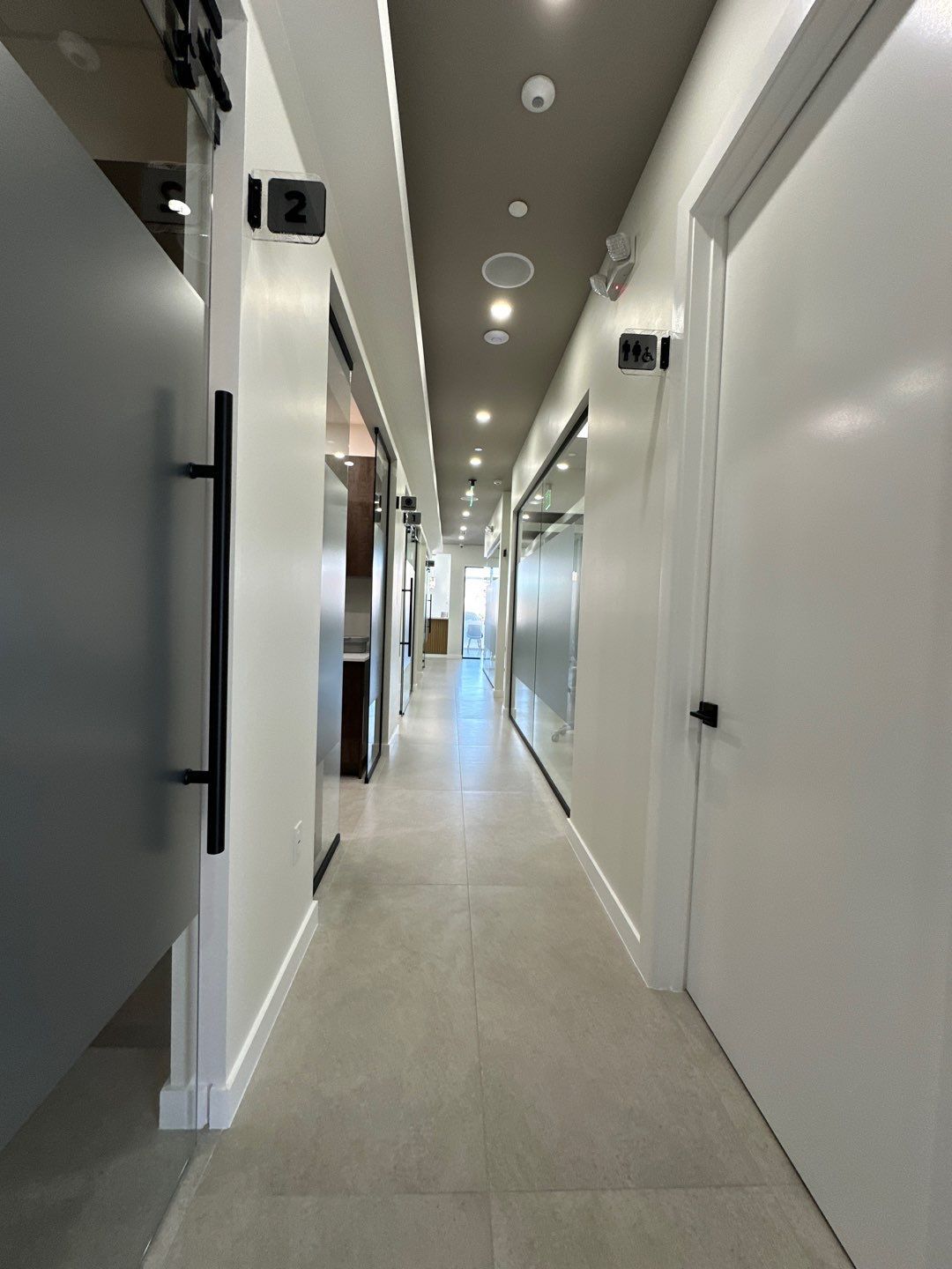 A long hallway with white walls and doors in a dental office.