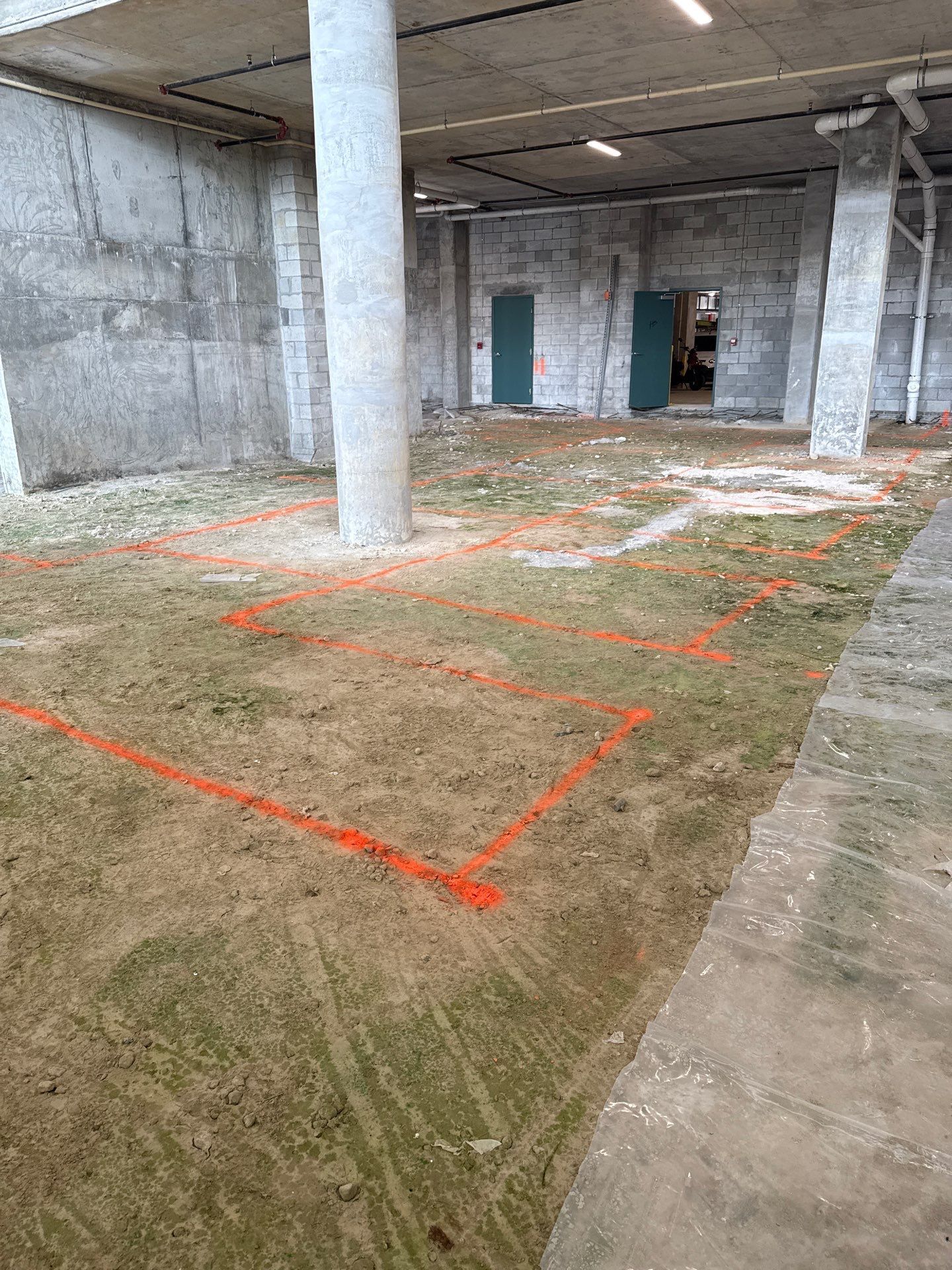 A large concrete room with a lot of dirt on the floor.