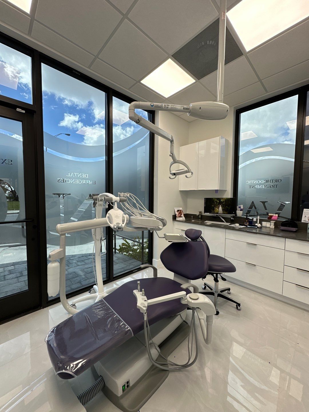 A dental office with a purple dental chair and a lot of windows