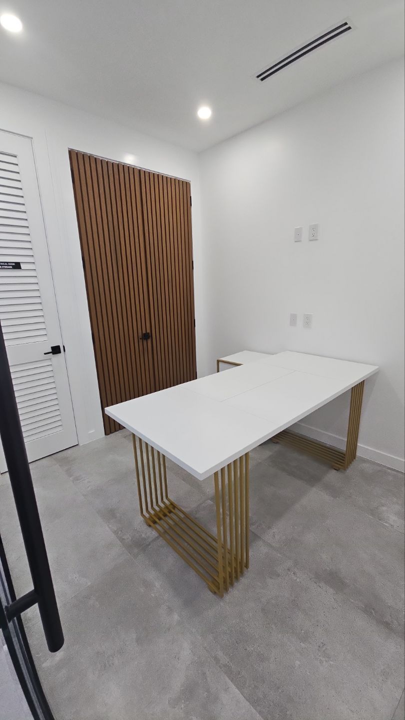 A white table with gold legs is sitting in a room.