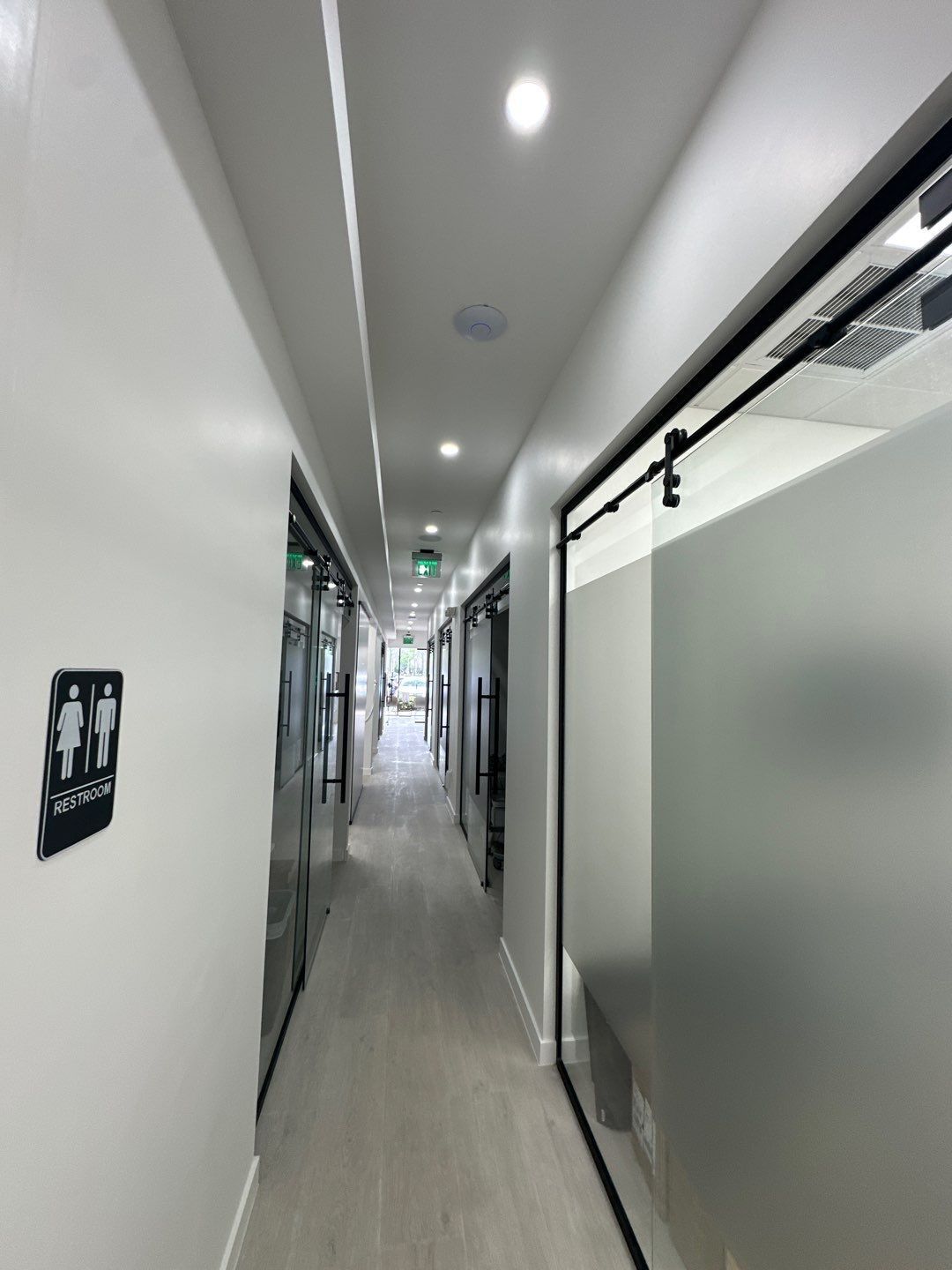 A long hallway with sliding glass doors and a sign on the wall.