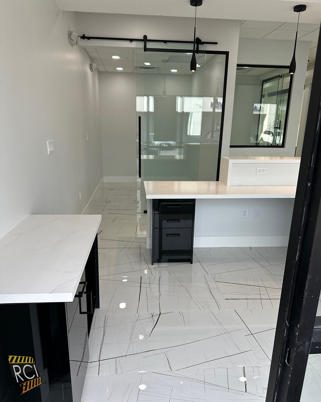 Empty modern kitchen with white cabinets, glossy tiled floor, and a large glass partition.