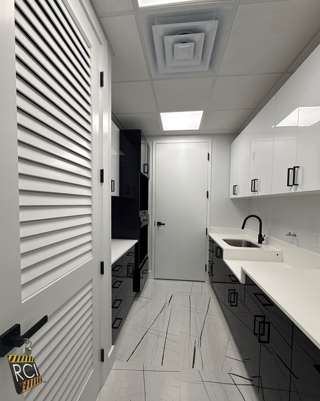 White laundry room with cabinets, sink, countertop, and louvered door under bright ceiling lights