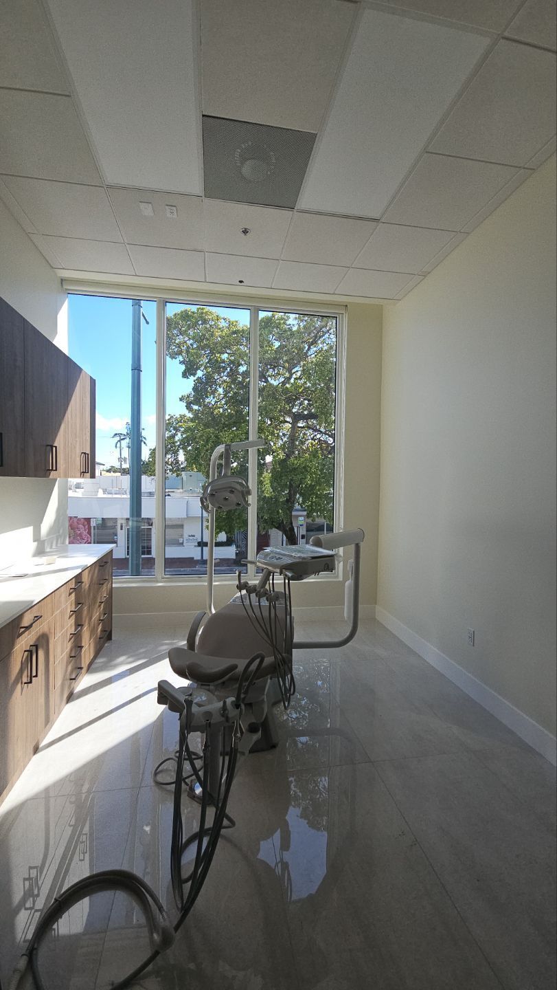 An empty dental office with a dental chair and a large window.