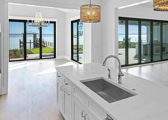 A kitchen with a sink , cabinets , and sliding glass doors.