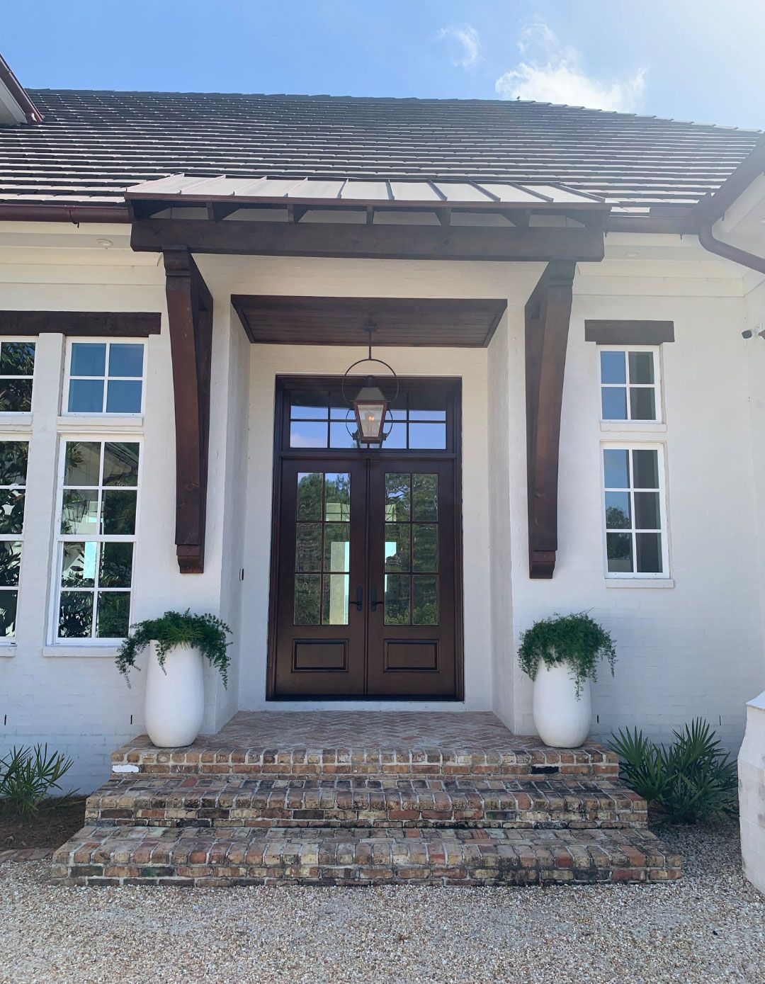 The front of a white house with a wooden door and brick steps.