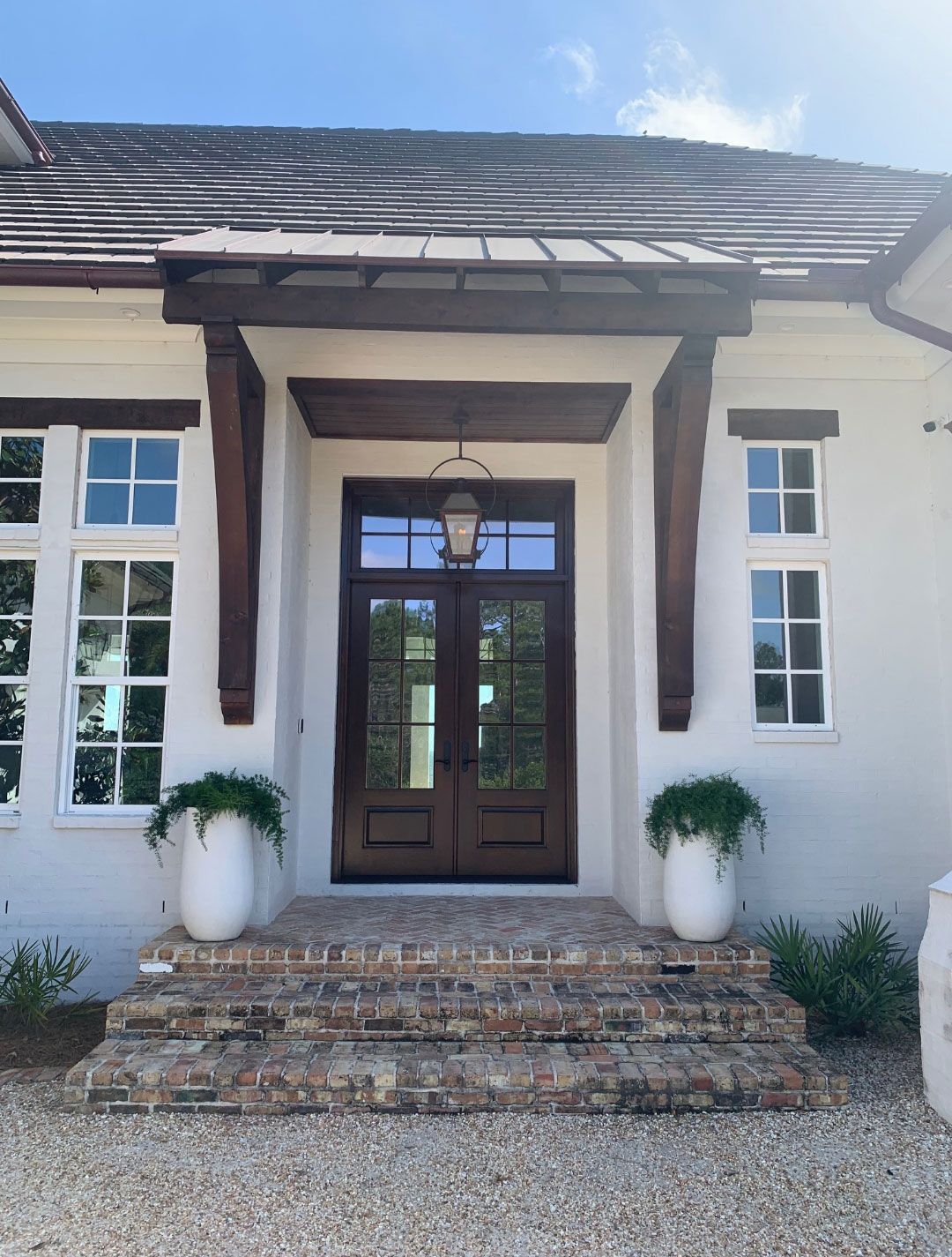 A white house with a brown door and a brick porch
