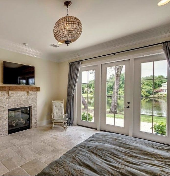 A bedroom with a bed , fireplace , television and sliding glass doors.