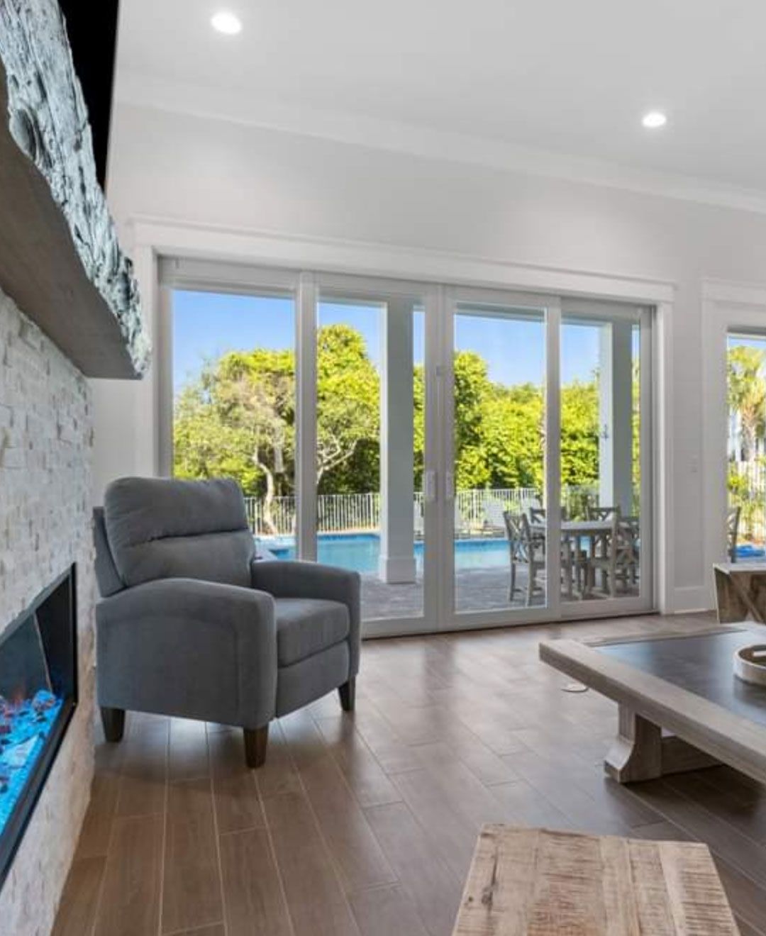 A living room with a chair , coffee table , fireplace and sliding glass doors.