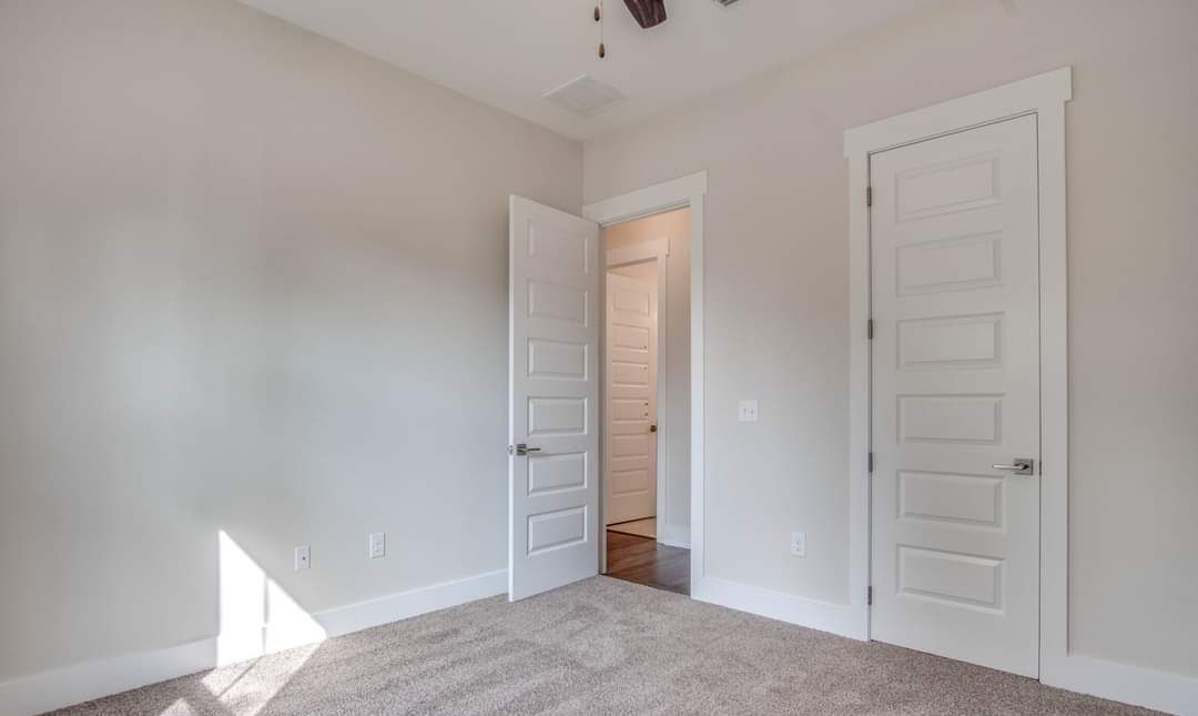 An empty bedroom with two white doors and a ceiling fan.