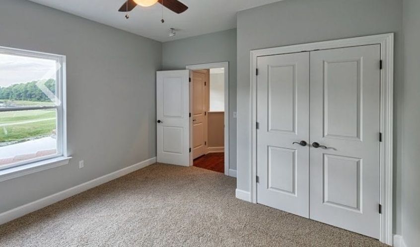 An empty bedroom with a ceiling fan and a window.