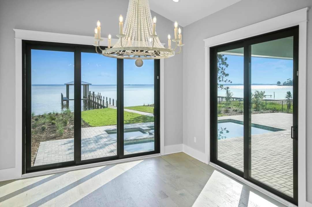 An empty room with sliding glass doors and a chandelier.