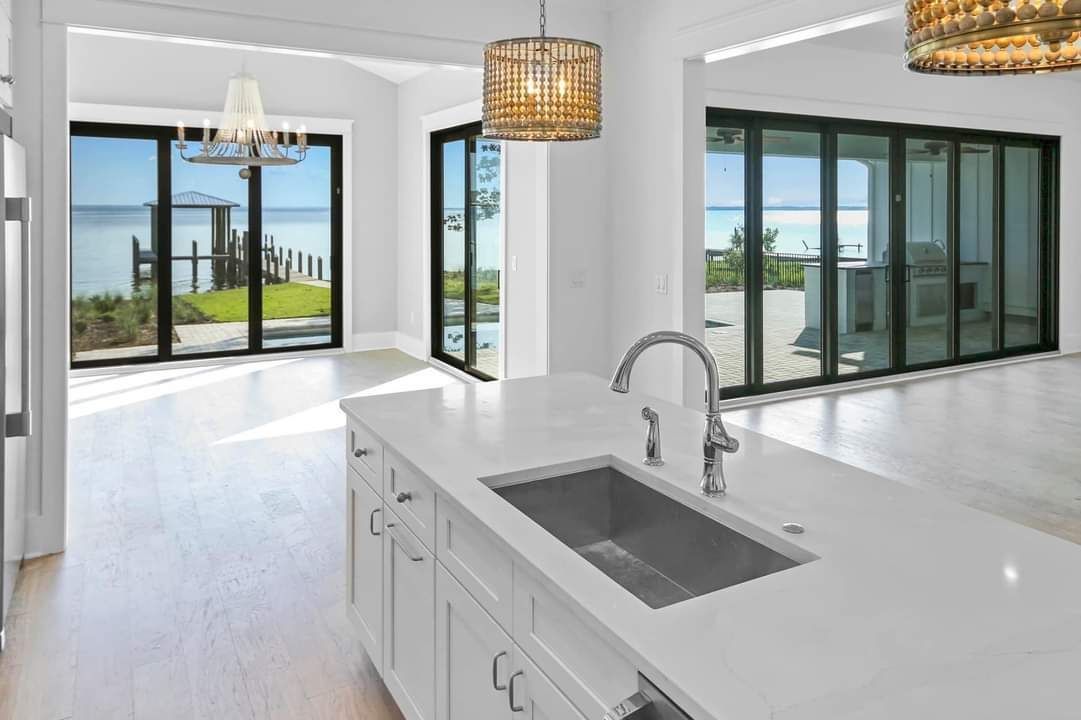 A kitchen with a sink , cabinets , and sliding glass doors.