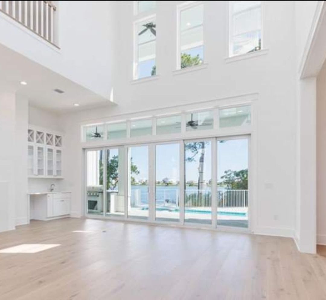 A large empty room with a lot of windows and a swimming pool in the background.