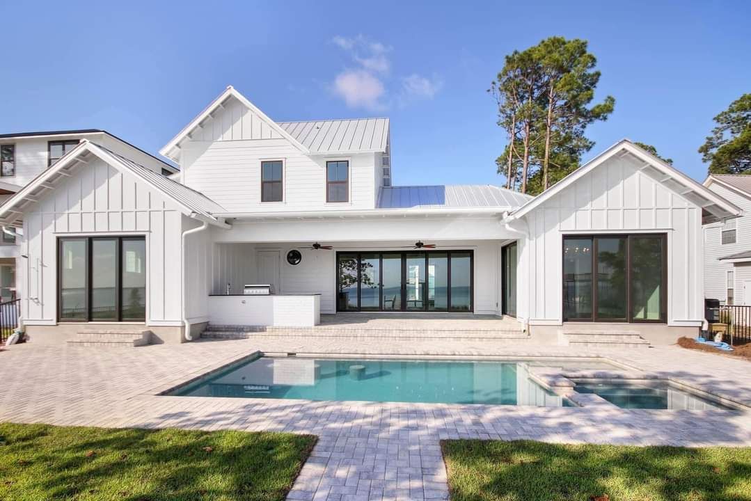 A white house with a large swimming pool in the backyard.