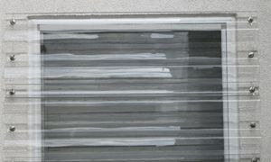 A close up of a window with clear shutters on a building.