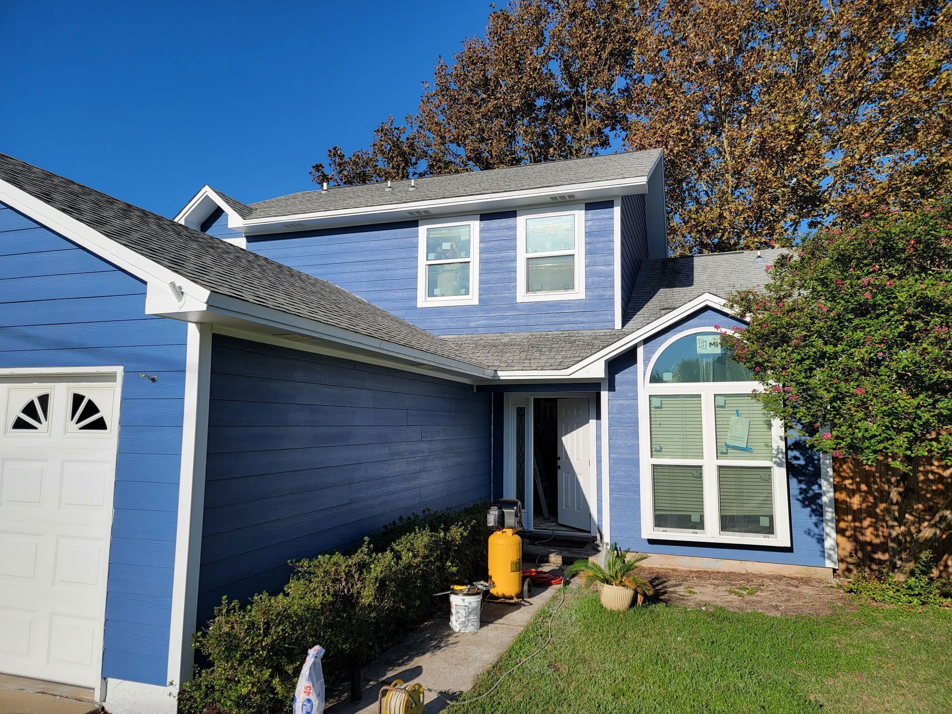 A blue house with a white garage door and a gray roof.