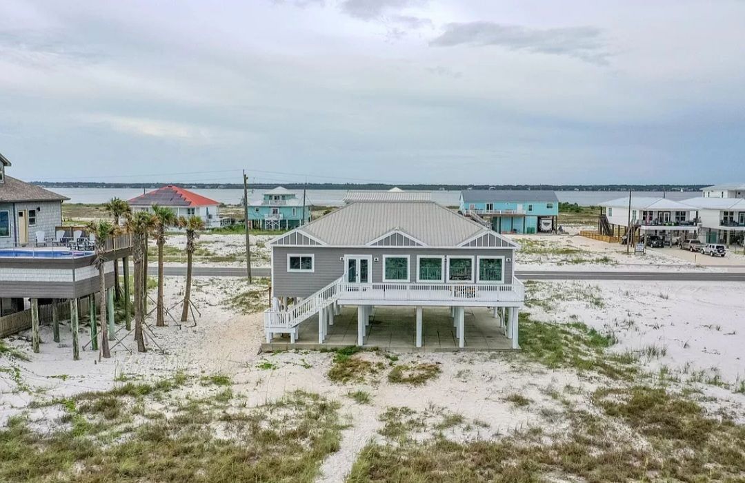 An aerial view of a house on stilts on the beach.