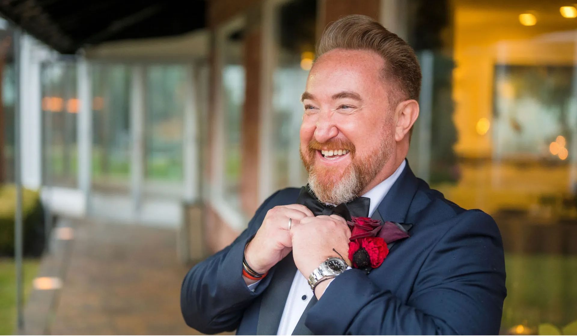 a man in a suit and bow tie is smiling while fixing his bow tie 