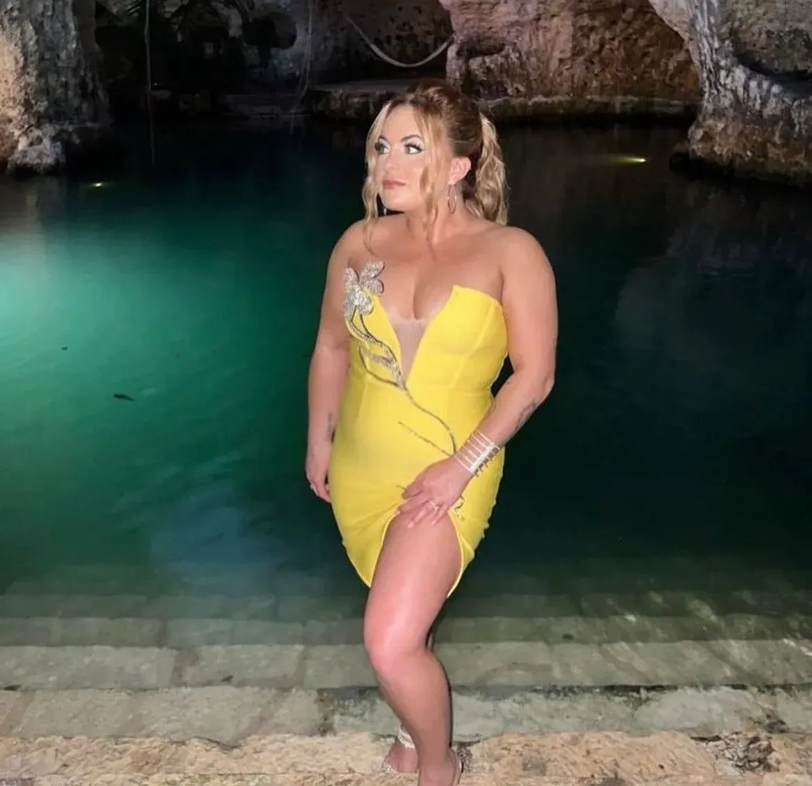 a woman in a yellow dress is standing next to a body of water