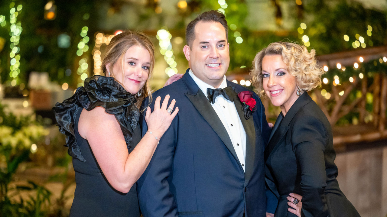 a man in a tuxedo is posing for a picture with two women