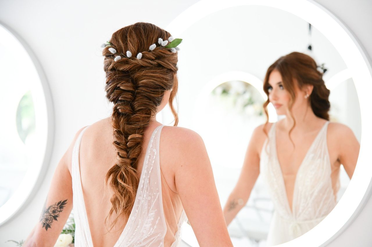 a woman in a wedding dress is looking at herself in a mirror