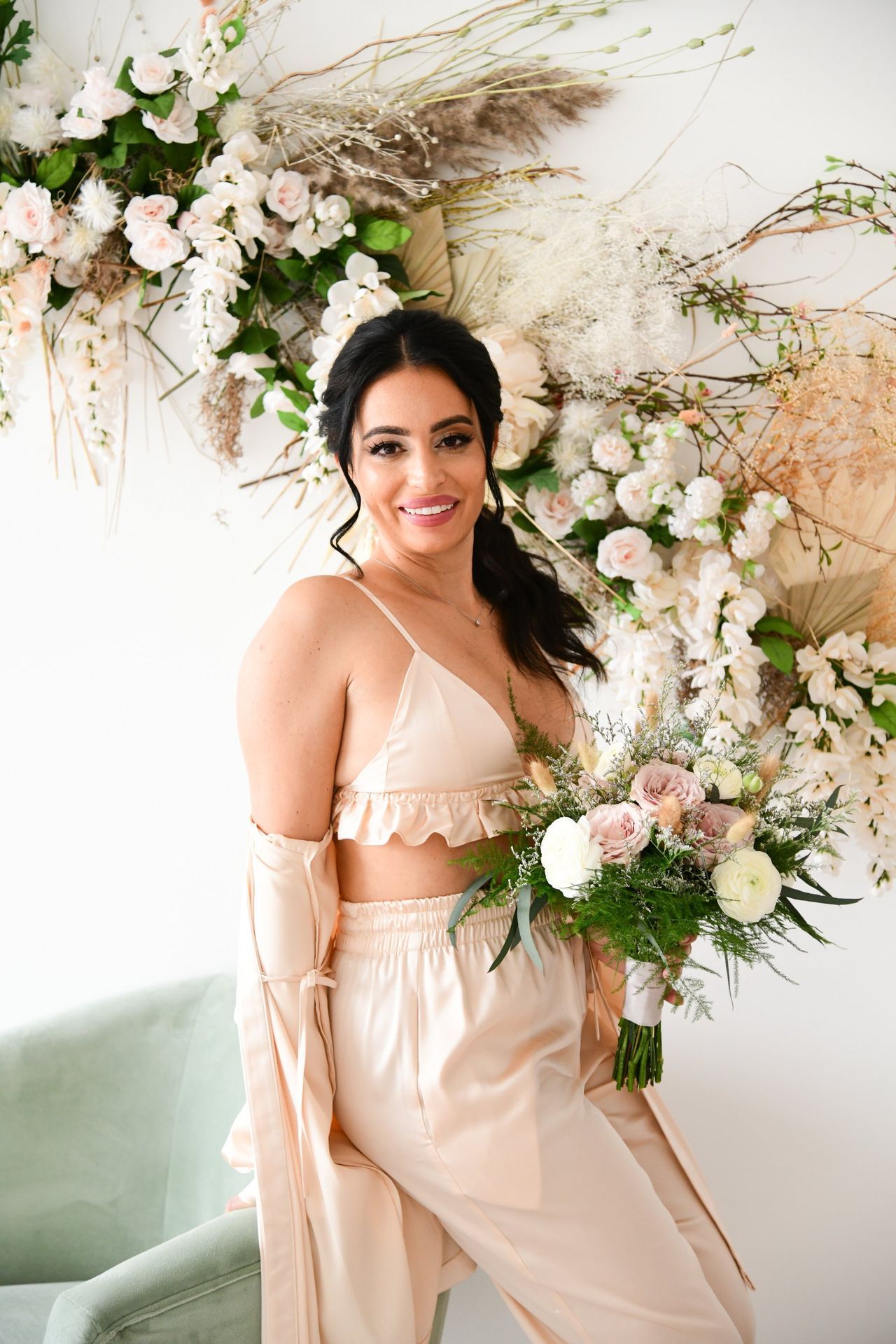 a woman in a crop top and pants is holding a bouquet of flowers